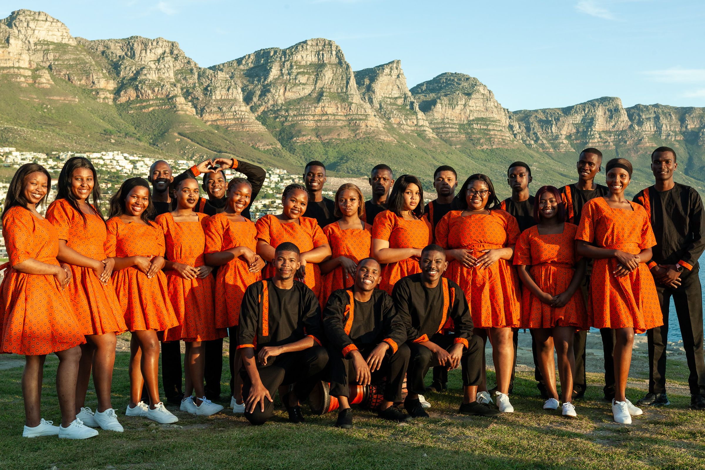 Lizwi Choir gathered together at Camps Bay, Cape Town, with the Twelve Apostles behind them.