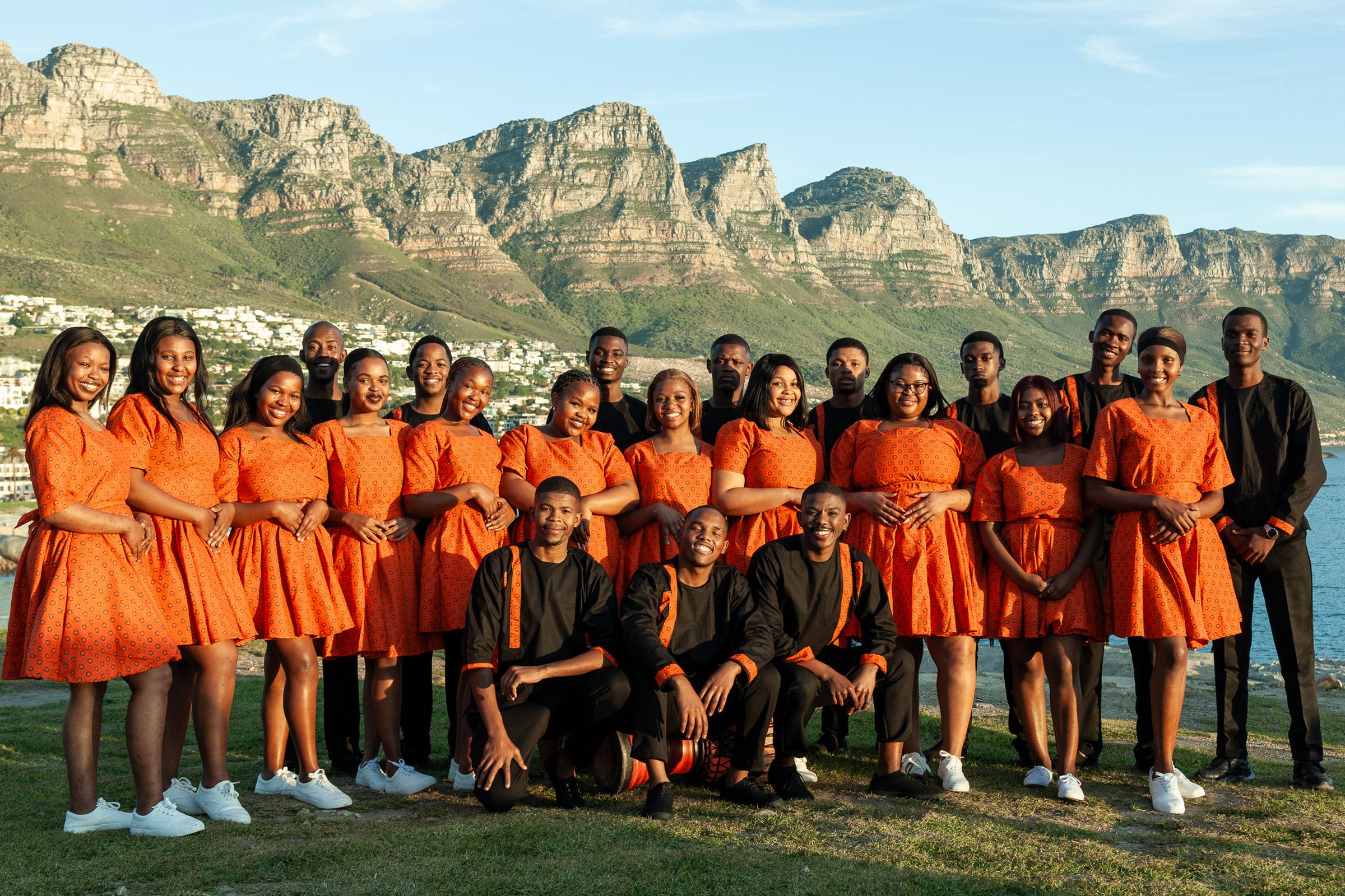 The members of Lizwi Choir, photographed together at Camps Bay, Cape Town, with the Twelve Apostles behind them.